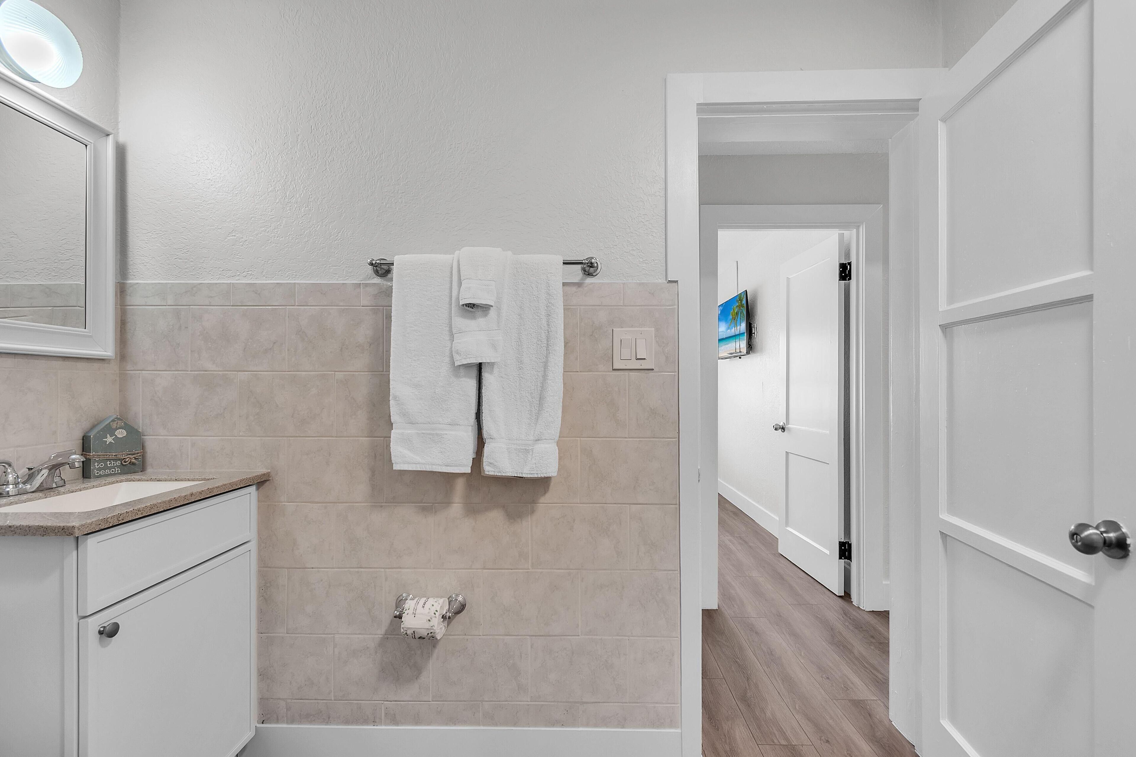 Un baño con baldosas color beige, un lavabo blanco y un perchero.