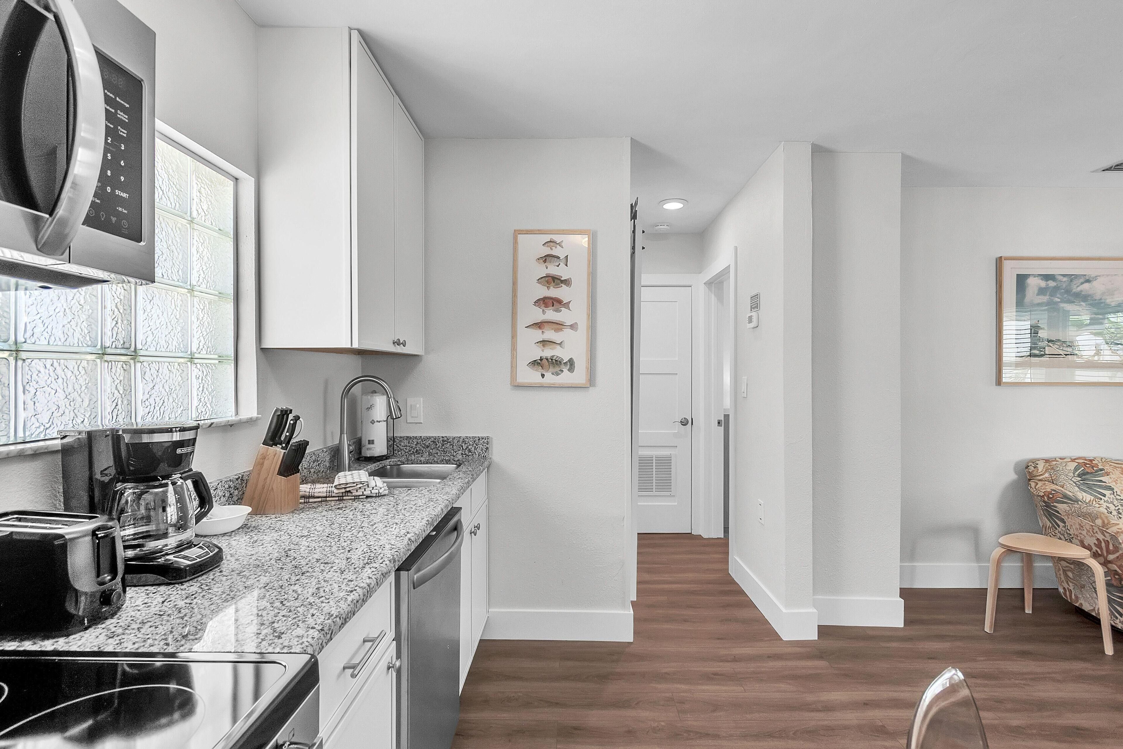 A modern kitchen with granite countertops, a built-in oven, and a coffee maker.