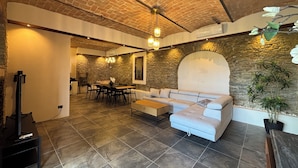 A spacious living area with a stone wall, a sofa, a dining table, and a television. - Relais Portaluna Incanto / 2BR, Sleeps 6, Garden, Langhe Views, Wifi (Piemonte)