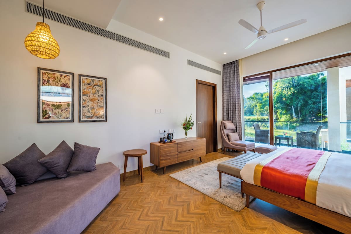 Une chambre moderne avec un grand lit, un canapé, une commode en bois et un ventilateur de plafond.