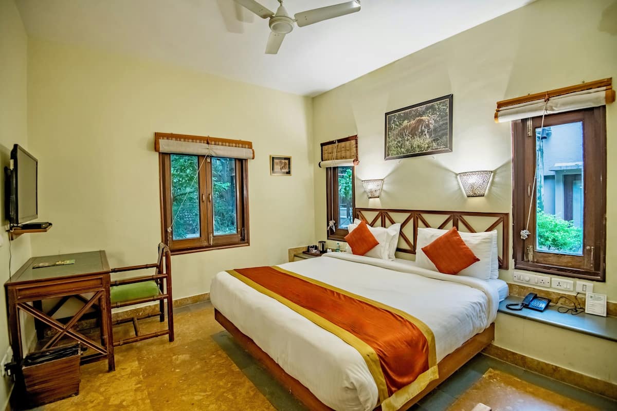 Une chambre d’hôtel équipée d’un lit, d’un bureau, d’une chaise et d’un ventilateur de plafond.