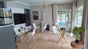 Un salon moderne comprenant un coin repas, une cheminée et de grandes fenêtres.
