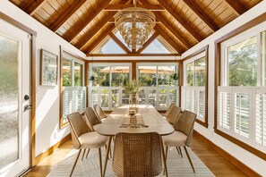 A dining area with a high ceiling, wooden beams, and large windows. - Langoon Lodge 3-BR 2-BA, 7 beds. Walk to DT&Lake (Mount Dora)