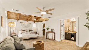 Un dormitorio espacioso con una cama grande, un ventilador de techo y una mesita de noche con lámpara.