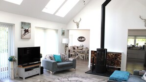 A modern living room with a flat-screen TV, grey sofa, and a fireplace. - Camden House Holidays Scottish Highlands Villa (Spean Bridge)
