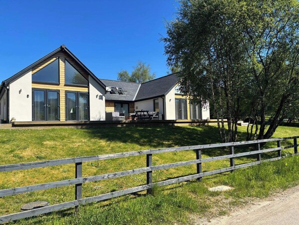 A modern two-story house with large windows and a covered patio area. - Camden House Holidays Scottish Highlands Villa (Spean Bridge)