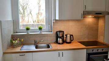 Cocina compacta con ventana, lavamanos, estufa y alacenas.
