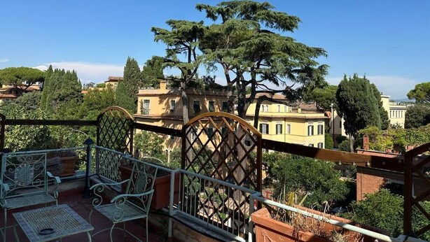 Una terraza con mobiliario exterior y vistas a edificios y árboles.
