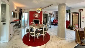 Una sala de estar moderna con una pared de acento roja, una mesa de comedor redonda y un pilar grande.