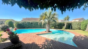 Una piscina con un pontile in legno e una palma.