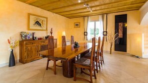 Zona pranzo con tavolo e sedie in legno, un armadietto con diversi oggetti e un quadro appeso al muro.
