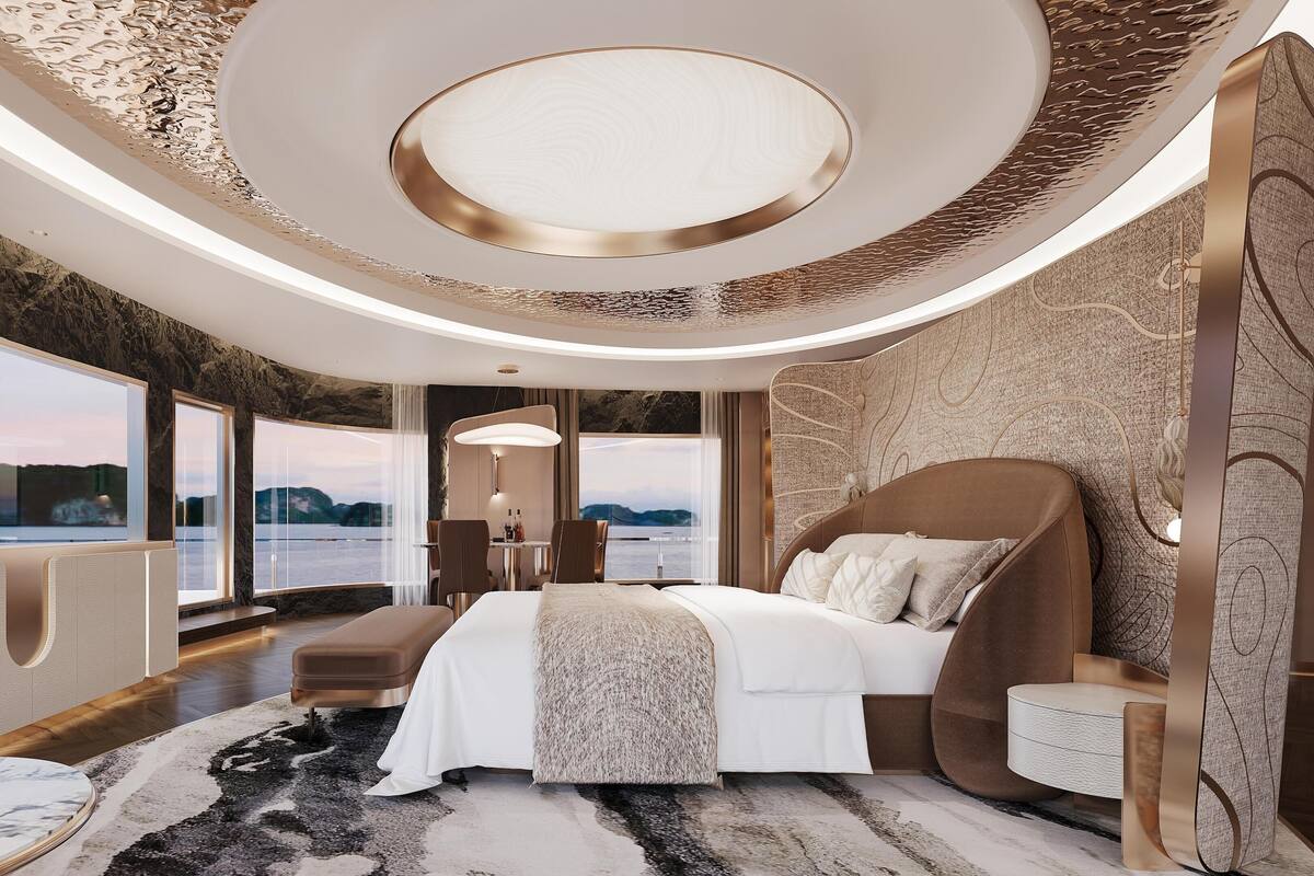 A modern hotel room with a large bed, a desk, and a view of the water.