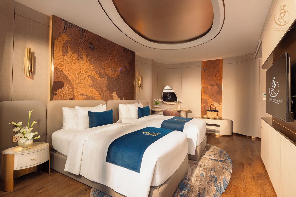 A modern hotel room with a large bed, bedside tables, a desk, and a TV.