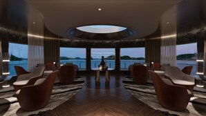A spacious room with a central table, seating, and large windows offering a view of the sea. - Athena Premium Cruise Halong Bay (Bai Chay)