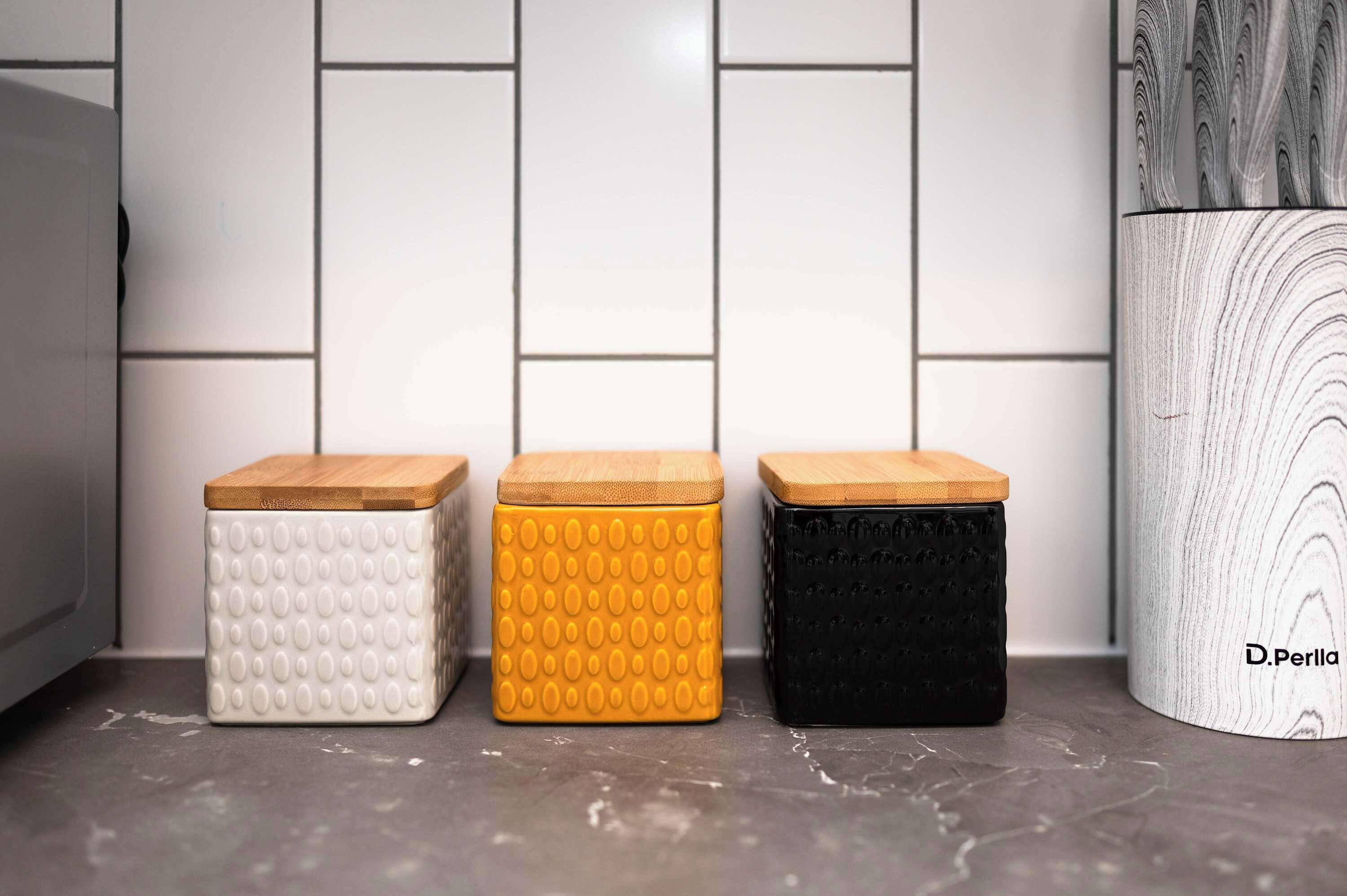 Drie opbergcontainers met houten deksels op een aanrecht.