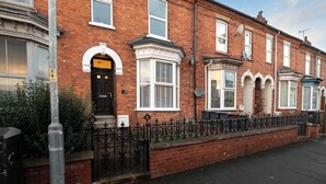 A row of terraced houses with distinct front doors, a brick facade, and a black metal fence. - Monks Quarters-Luxe 3 Bed, Private Parking x2 Cars (Lincolnshire)