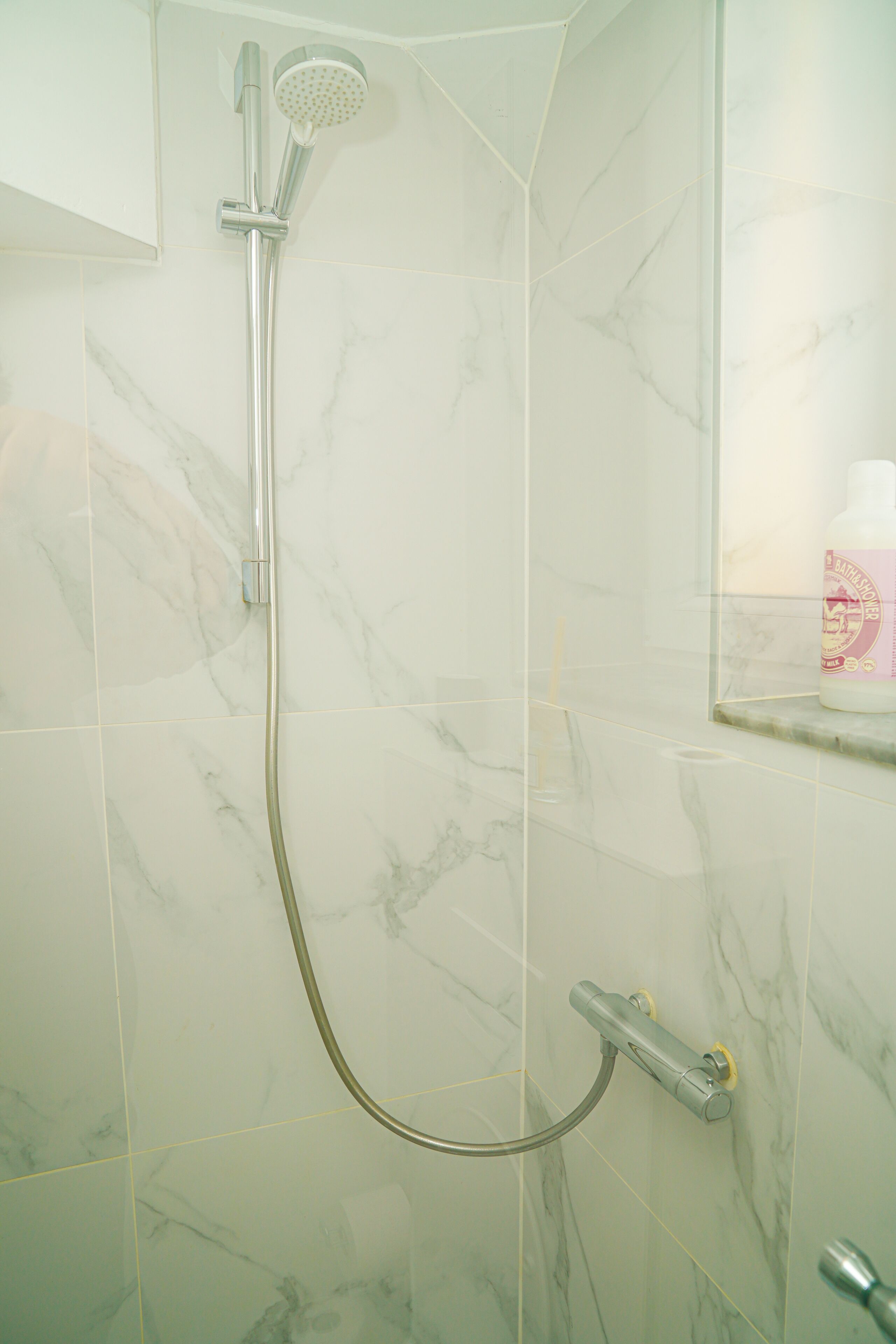 A bathroom with a shower, a toilet, and a mirror.
