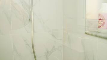 A bathroom with a shower, a toilet, and a mirror.