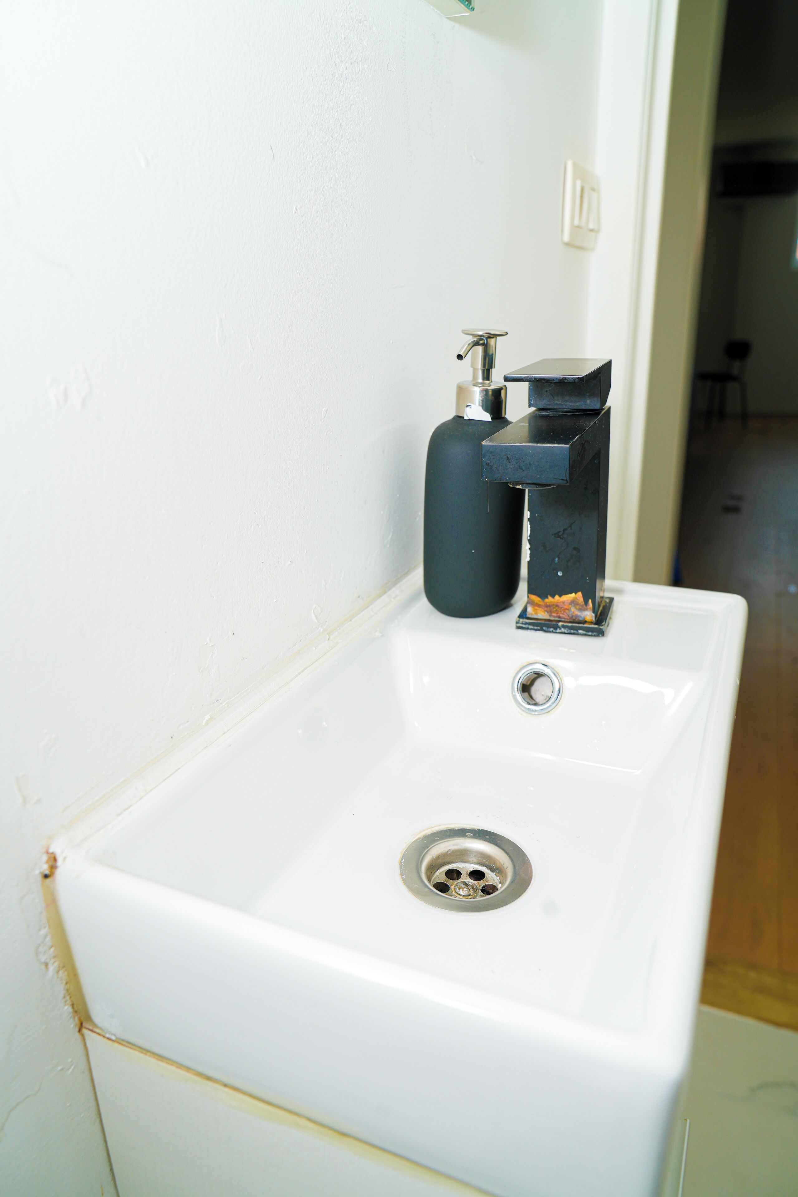 A white bathroom sink with a modern faucet and a black soap dispenser.