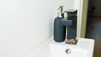 A white bathroom sink with a modern faucet and a black soap dispenser.