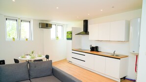 A modern kitchen with white cabinets, a black range hood, and a wooden countertop. - Cozy 1BR With Living Room Near City (Ghent)