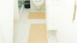 Un baño moderno con cabina de ducha de vidrio, inodoro y tocador blanco con espejo.