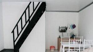 A modern living room with a staircase, a dining area, and a kitchen in the background. - Lotus Nexura Escape (Kejajar)
