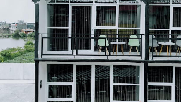 A two-story building with large windows and balconies, featuring outdoor seating and potted plants. - Lotus Nexura Escape (Kejajar)
