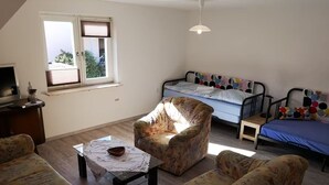 Un espacio habitable compacto con un sofá, un sillón y una cama con ropa de cama estampada.