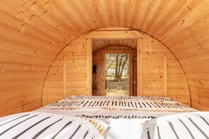 An arched wooden room with a bed and a door leading outside. - Le Tonneau des Chouchous (Hourtin)