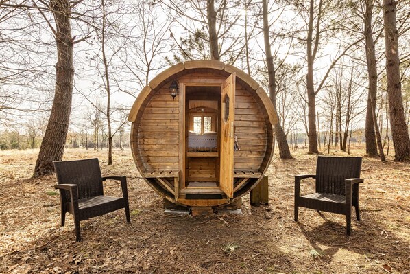 A wooden structure with an open door, two chairs, and a bench outside. - Le Tonneau des Chouchous (Hourtin)