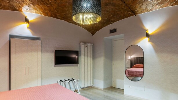 A bedroom with a bed, a TV, a wardrobe, a radiator, and a mirror. - GuestHost - A modern and welcoming 55 square meters apartment, perfect for four people, located on the ground floor of a building with an elevator (NOT accessible for disabled guests and not necessary to access the apartment). The property is just steps  (Rome)