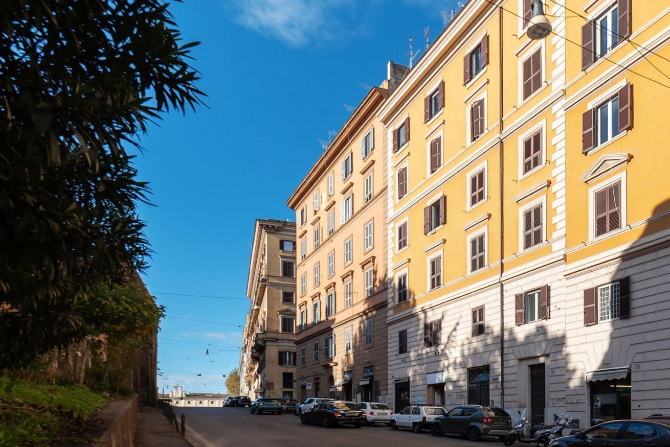 Eine Straße mit gelben Gebäuden, parkenden Autos und blauem Himmel.