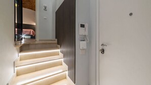 A staircase with a handrail, a door with a lock, and a wall-mounted intercom. - GuestHost - A modern and welcoming 55 square meters apartment, perfect for four people, located on the ground floor of a building with an elevator (NOT accessible for disabled guests and not necessary to access the apartment). The property is just steps  (Rome)