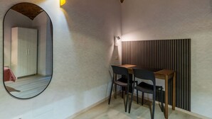 A room with a round mirror, a wooden table, two chairs, and a wall-mounted light fixture. - GuestHost - A modern and welcoming 55 square meters apartment, perfect for four people, located on the ground floor of a building with an elevator (NOT accessible for disabled guests and not necessary to access the apartment). The property is just steps  (Rome)