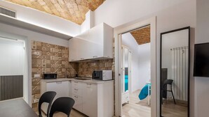 A modern kitchen with white cabinets, a microwave, and a dining area with two chairs. - GuestHost - A modern and welcoming 55 square meters apartment, perfect for four people, located on the ground floor of a building with an elevator (NOT accessible for disabled guests and not necessary to access the apartment). The property is just steps  (Rome)