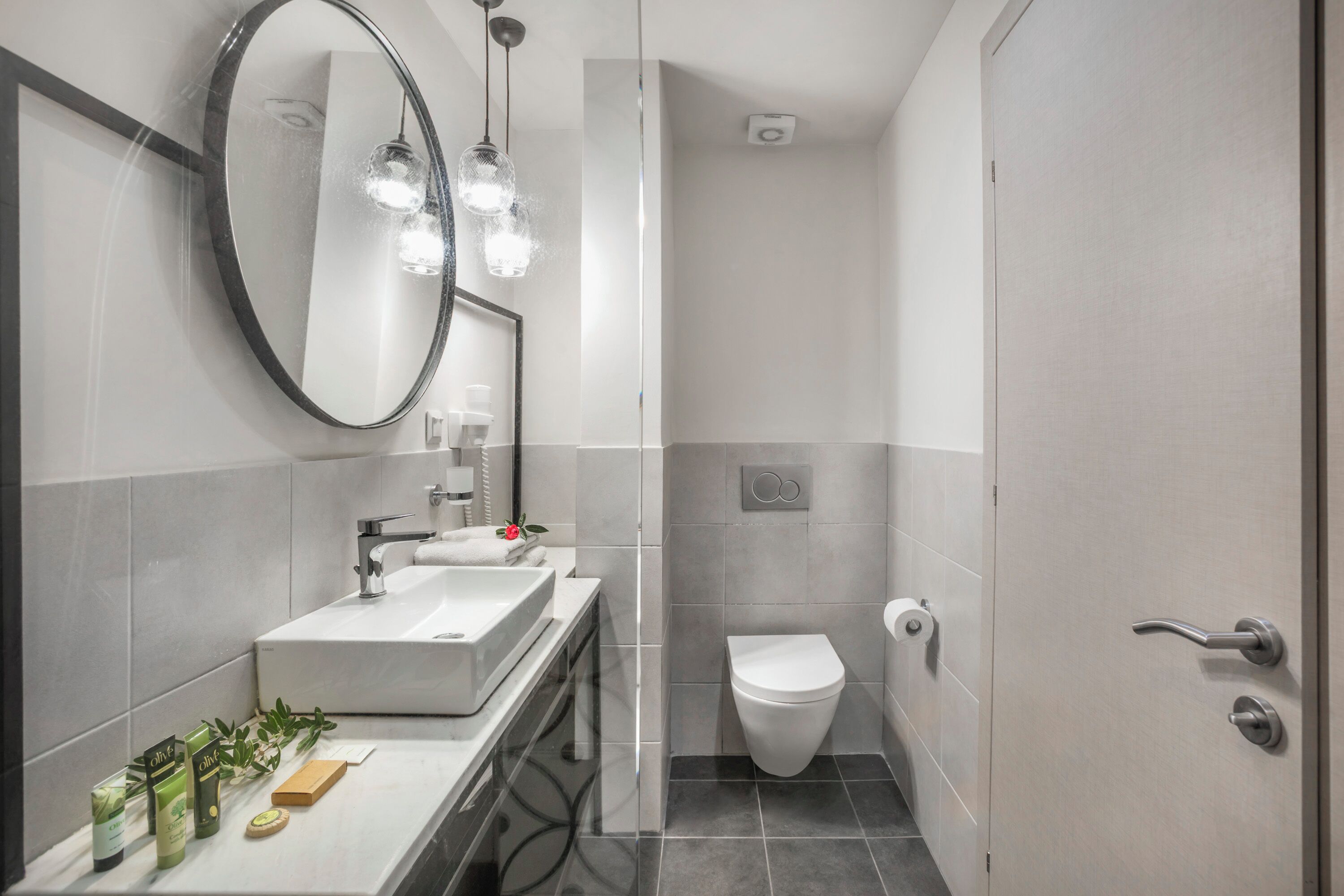 A modern bathroom with a sink, mirror, and toilet.