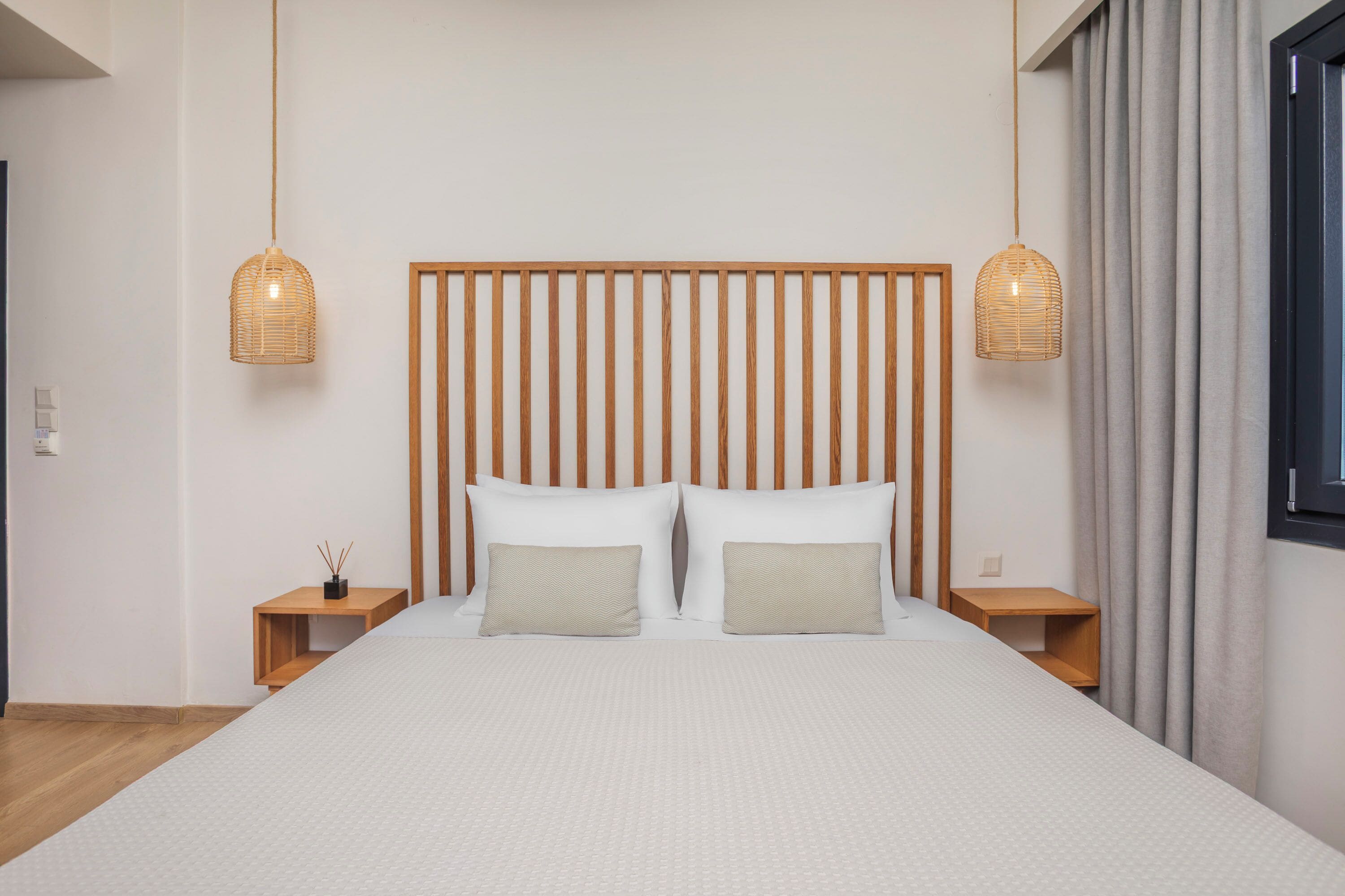 A modern bedroom with a large bed, wooden headboard, two bedside tables, and hanging wicker lamps.