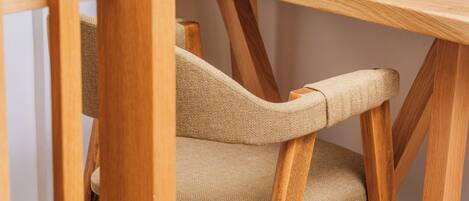 Una silla de madera con asiento y respaldo texturizados, ubicada debajo de una mesa de madera.