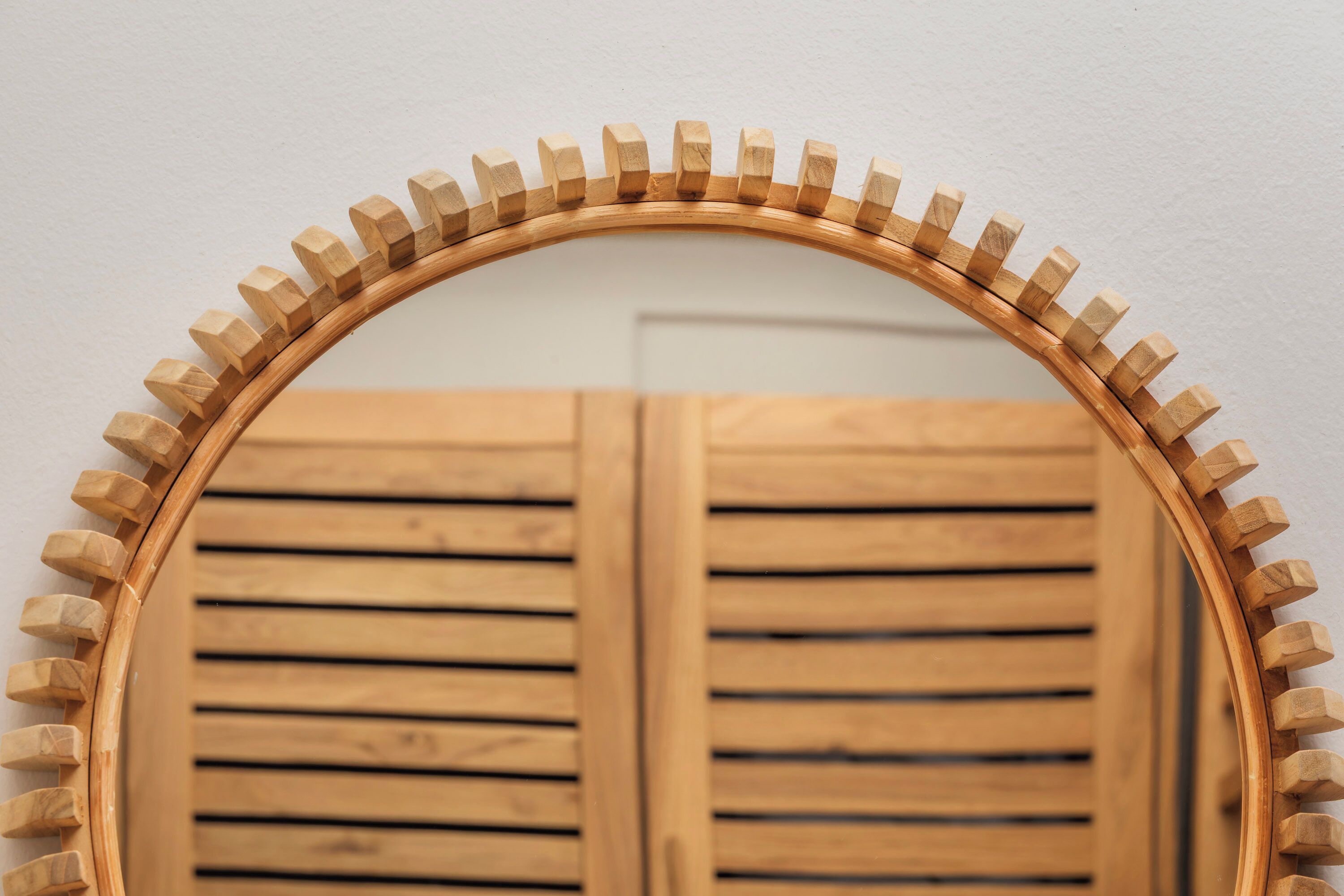 A wooden-framed mirror with a curved top and a wooden border.