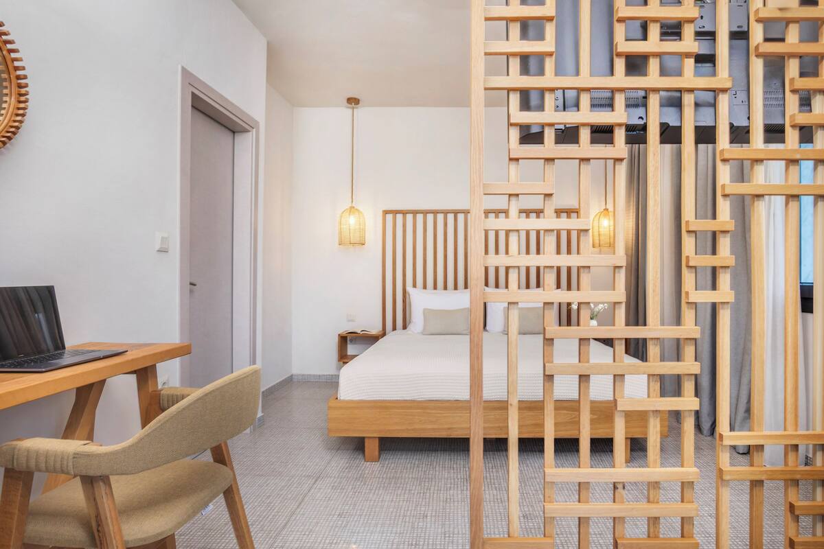 Un dormitorio con una cama de madera, un escritorio con silla y una estantería en la pared.