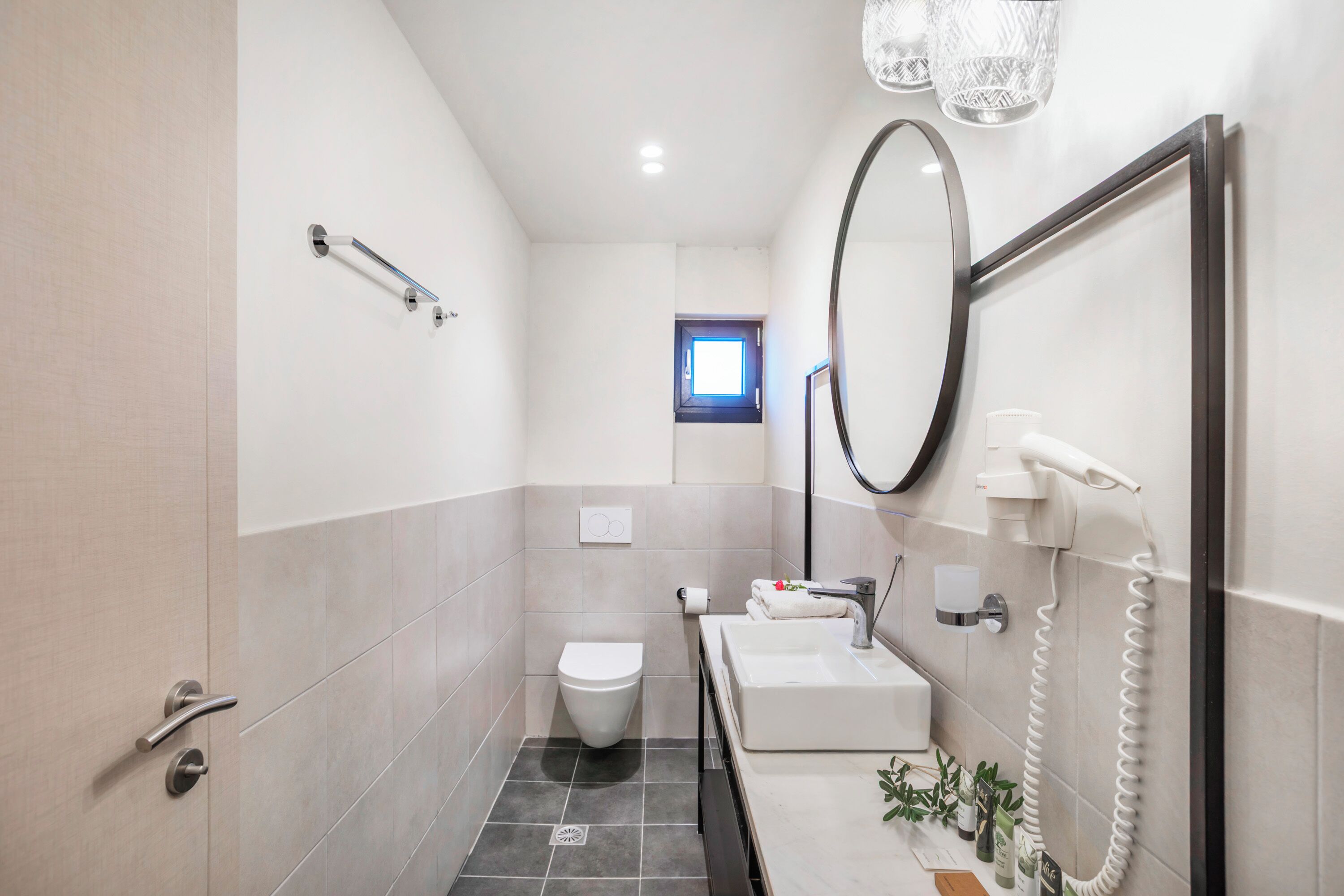 Een kleine badkamer met toilet, wastafel en spiegel.