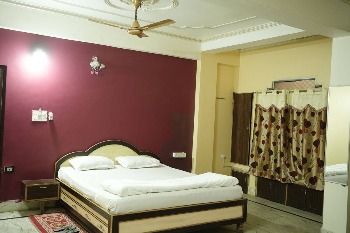 A bedroom with a bed, a ceiling fan, a nightstand, a wardrobe, and a curtain.