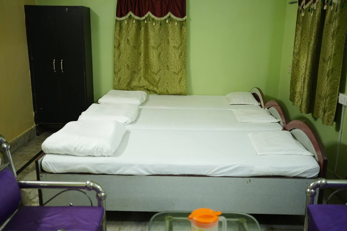 A single bed with white bedding, a black wardrobe, and purple chairs.