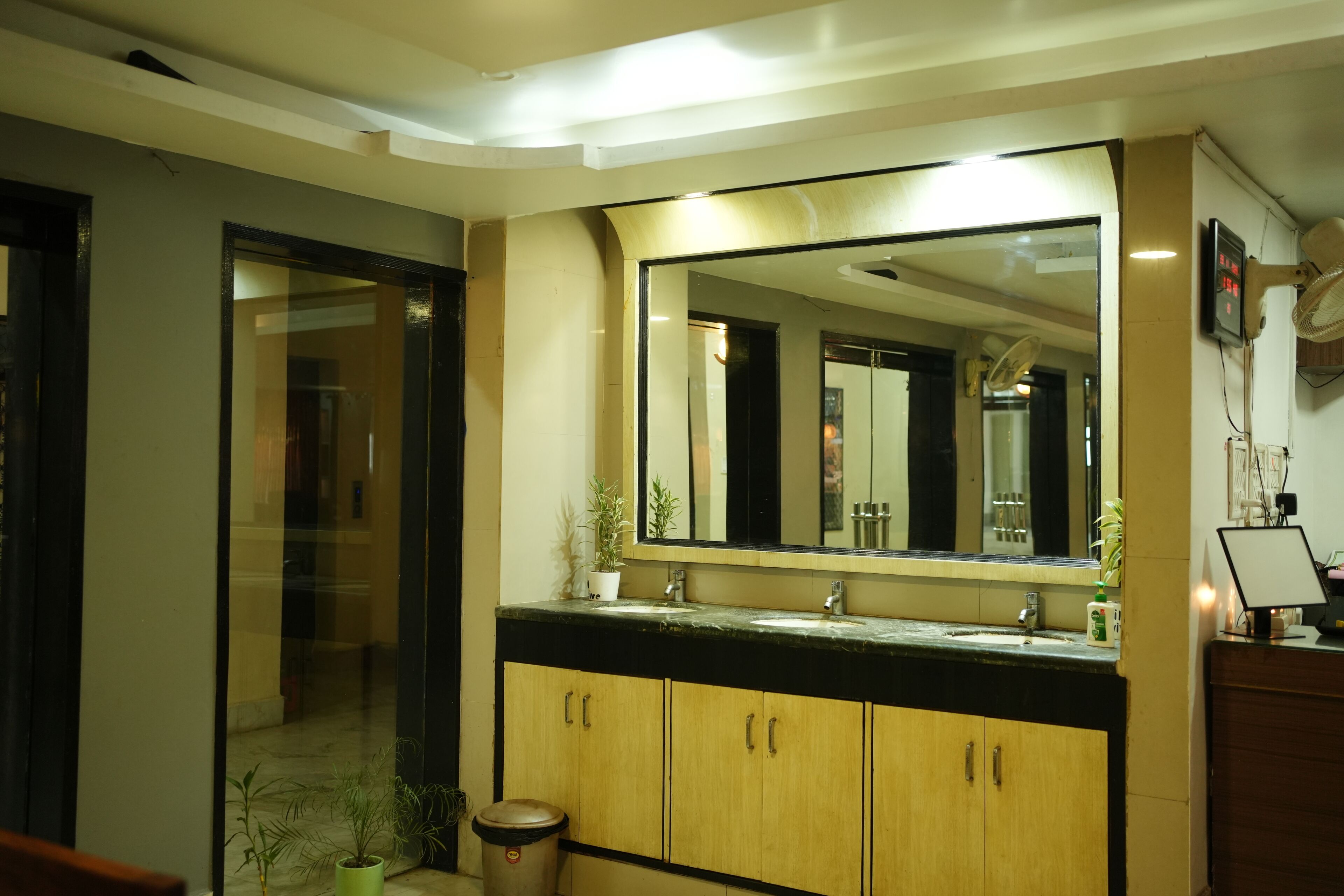 Une salle de bain avec un grand miroir, des meubles en bois, un lavabo et une poubelle.