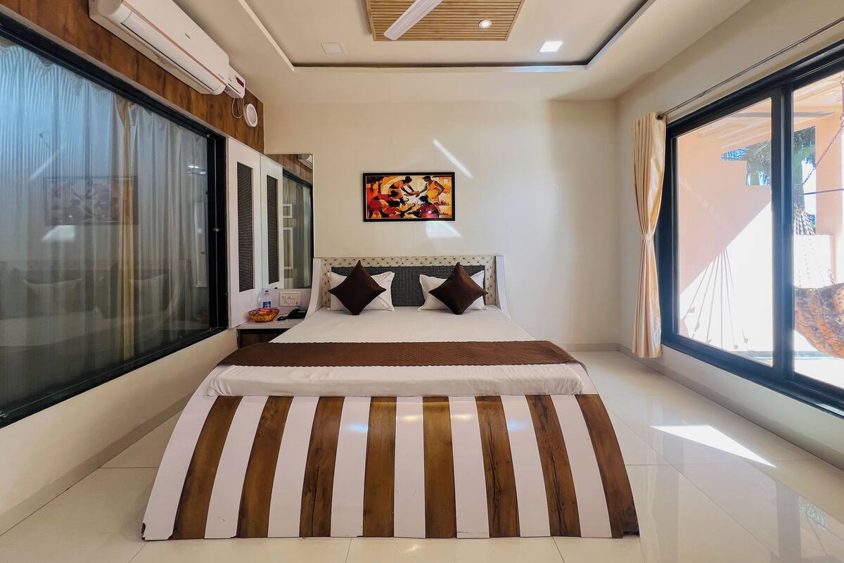 A modern bedroom with a large bed, a ceiling fan, and a window with a view.