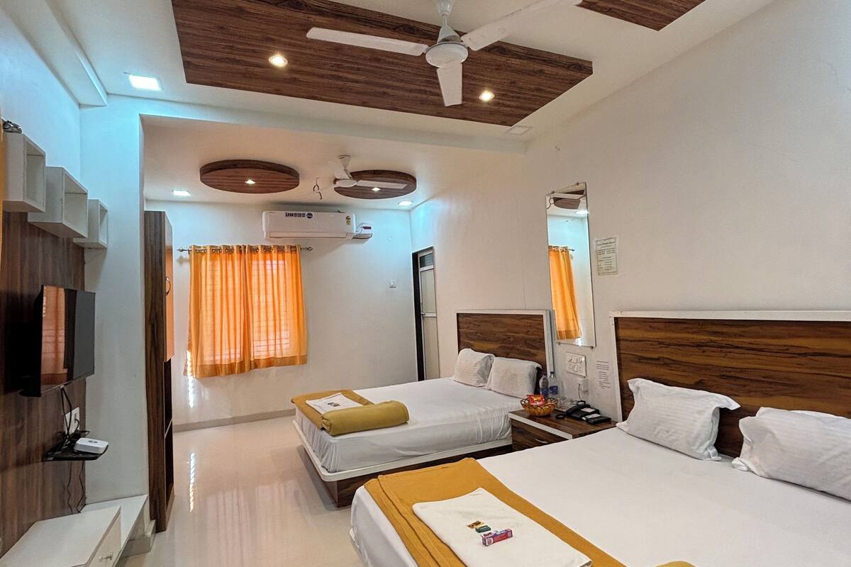 A hotel room with two beds, a ceiling fan, recessed lighting, a flat-screen TV, and a minibar.