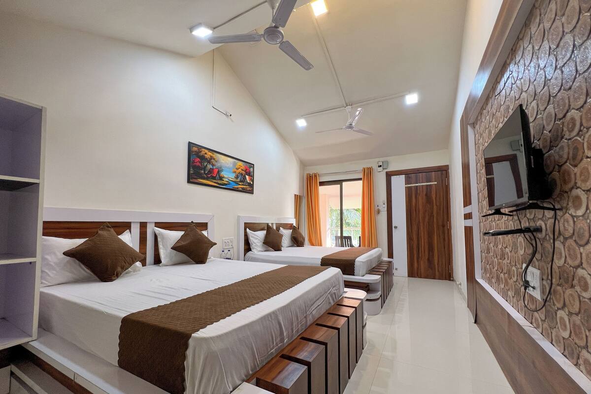 A hotel room with two beds, a ceiling fan, a painting, a TV mounted on the wall, and a balcony with curtains.