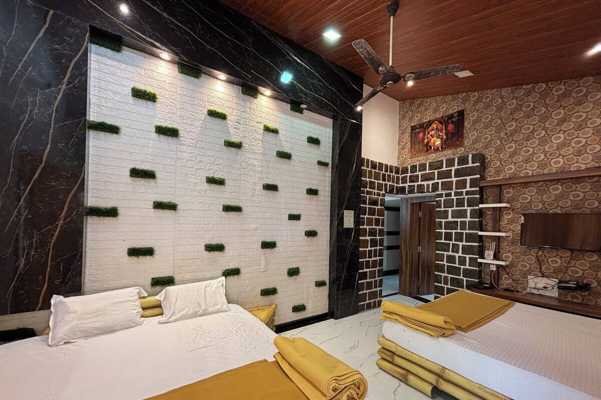 A hotel room with two beds, a large wall with green planters, a wooden ceiling, and a stone-patterned wall.