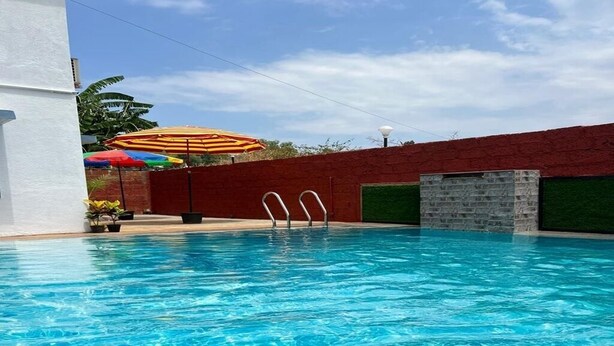 Una piscina con agua azul cristalina, un muro de ladrillo rojo y una pequeña construcción de ladrillo.